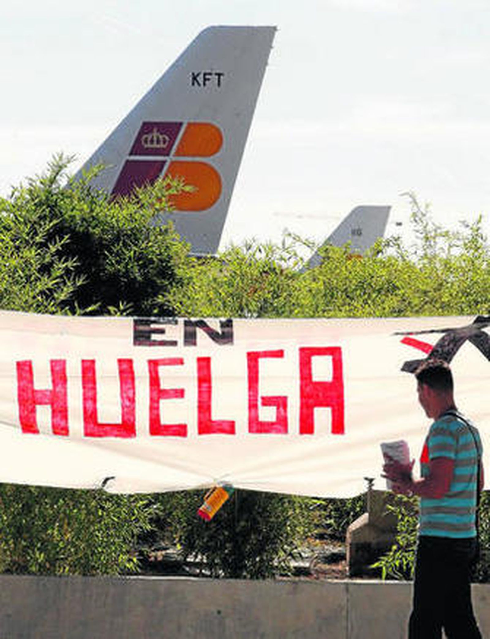 Un viajero pasa delante de uno de los carteles de los trabajadores de Iberia en el aeropuerto de Barajas.