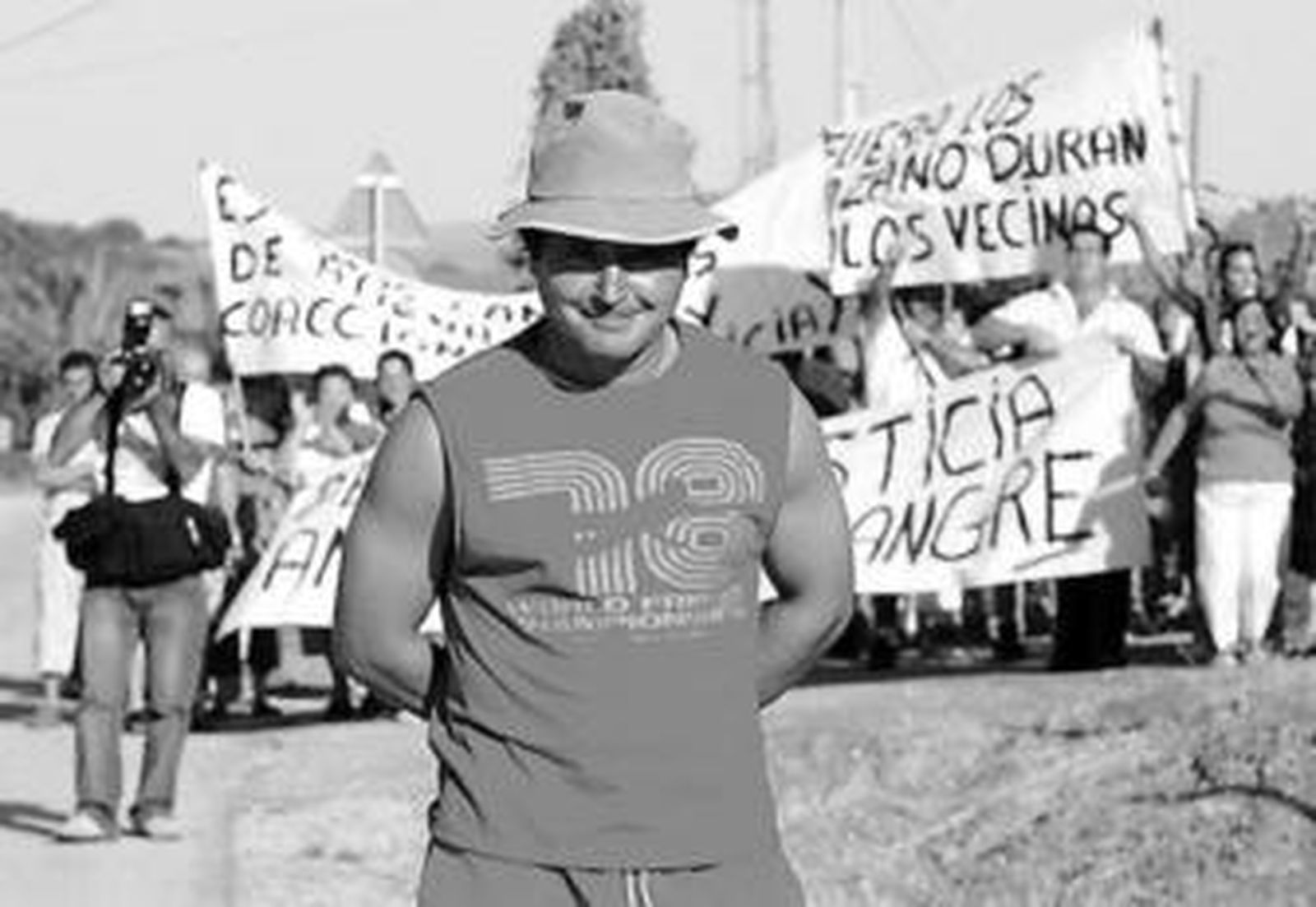En primer plano, el vecino denunciado. Al fondo, sus convecinos de Las Pachecas manifestándose contra él.