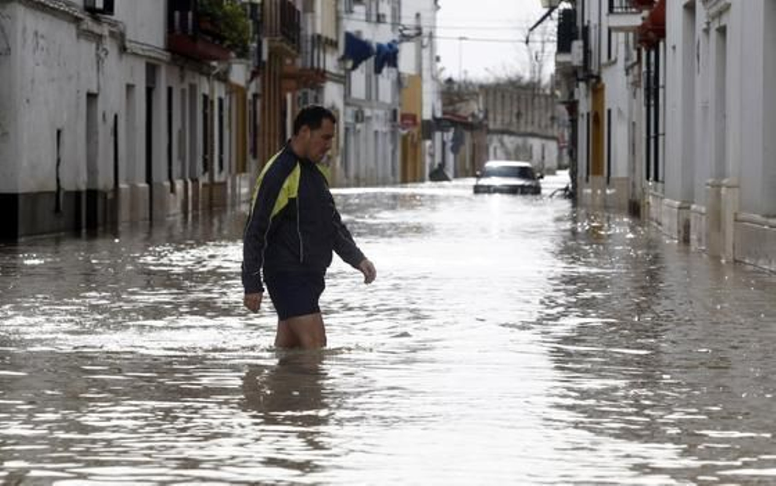 Un vecino intenta caminar por las inundadas calles de Écija y un coche se qeuda atrapado en el agua.

Foto: Antonio Pizarro