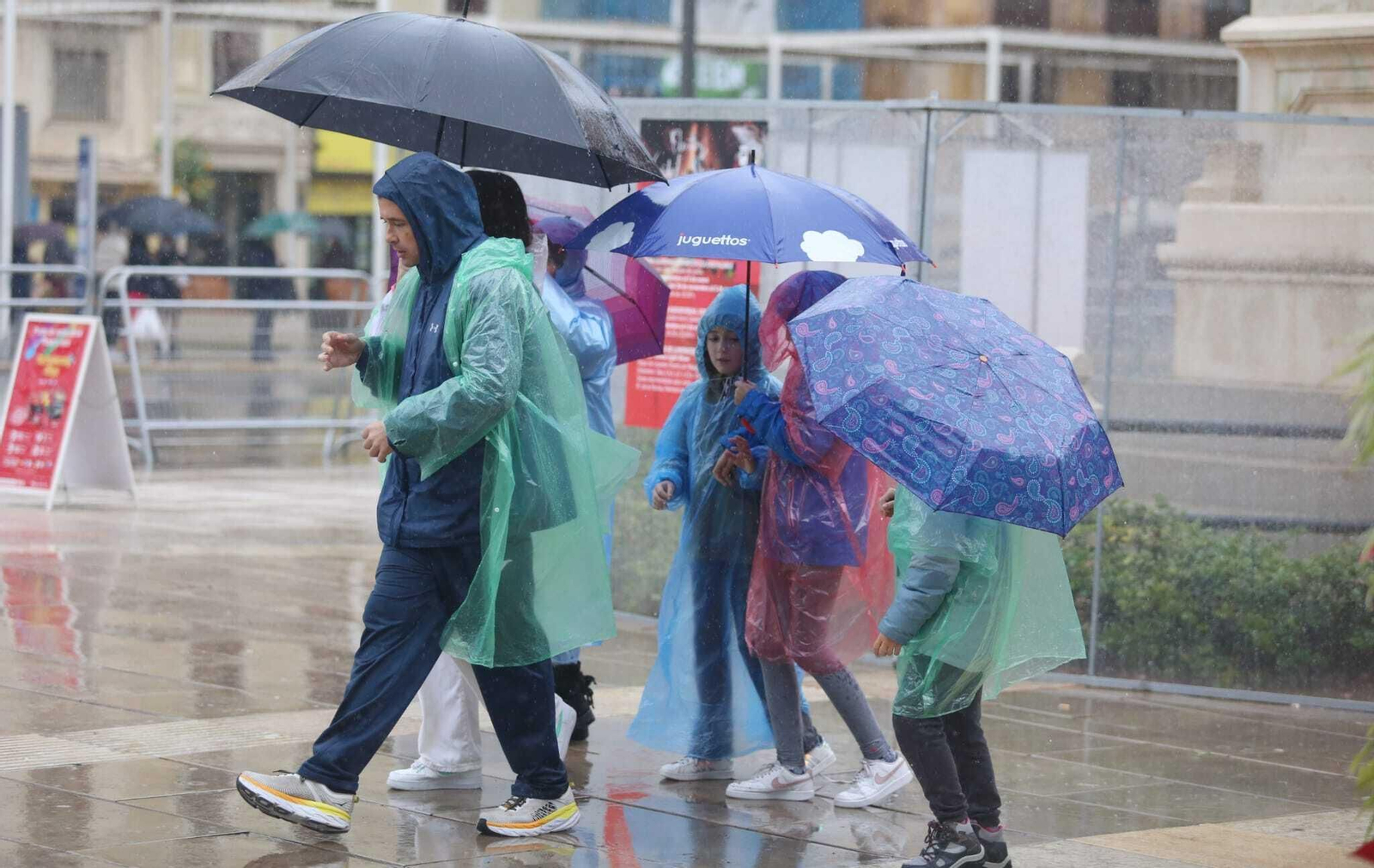 Una familia se protege de la lluvia en la Alameda Principal este viernes. Una familia se protege de la lluvia en la Alameda Principal este viernes.