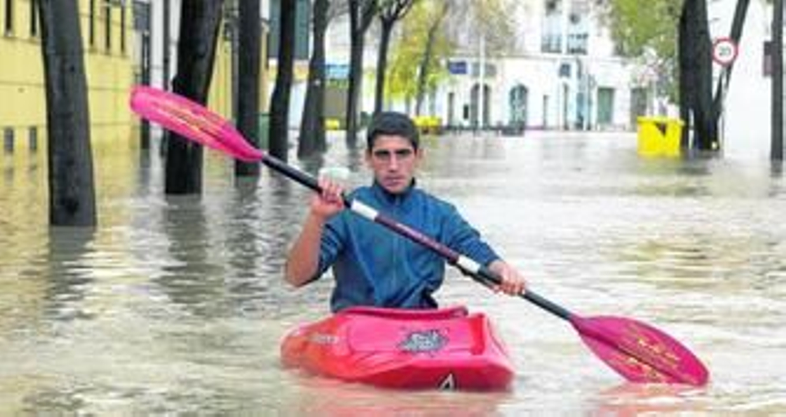 Un joven ecijano cruza en piraguas una de las las calles de la localidad totalmente inundada por el río Genil.
