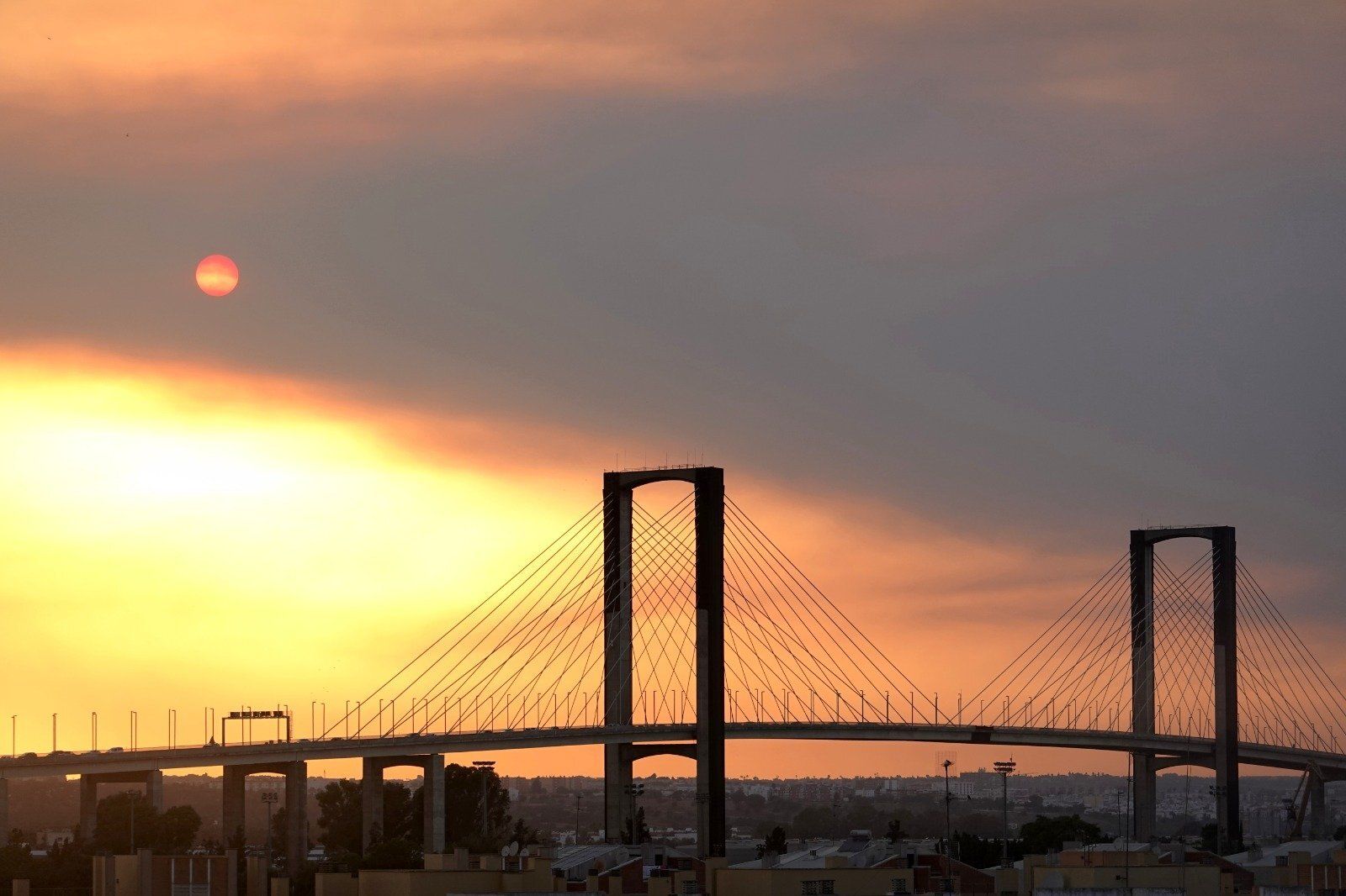 Tonos rojizos y anaranjados en el cielo de Sevilla, con el Puente del Centenario delante.