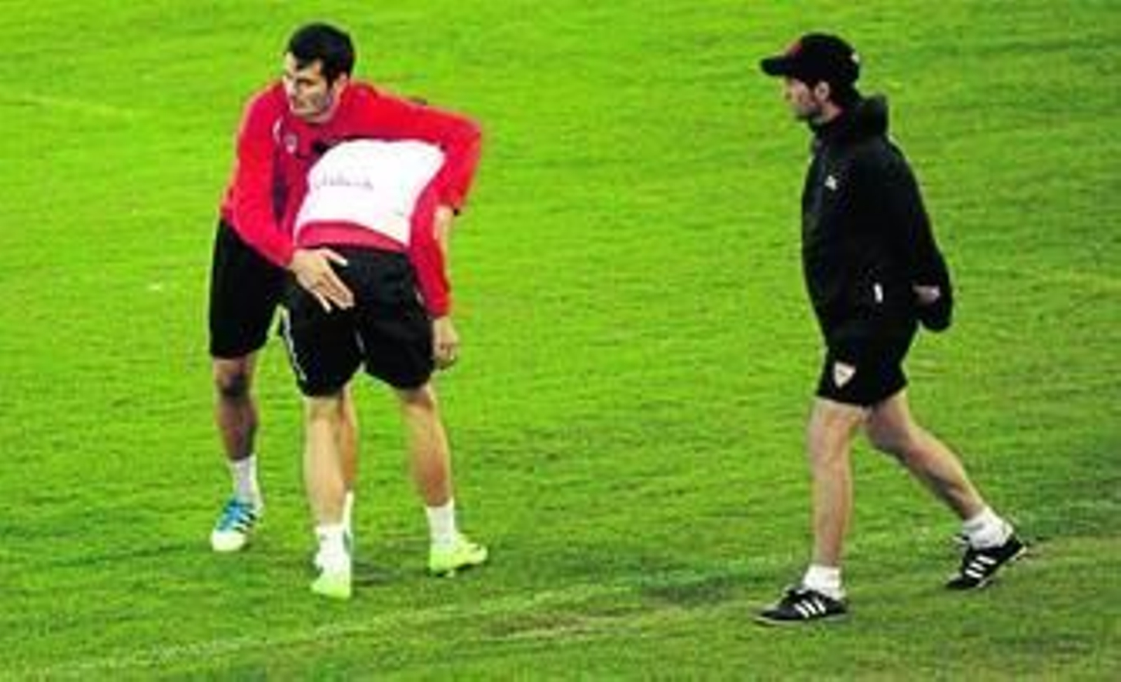 Spahic bromea con Luis Alberto, de espaldas, mientras Marcelino sigue el entrenamiento protegido con chubasquero y gorra.