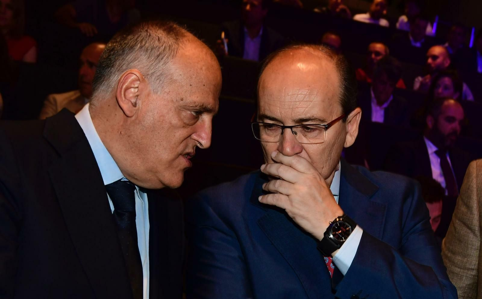 José Castro y Javier Tebas se realizan una confidencia en un acto.