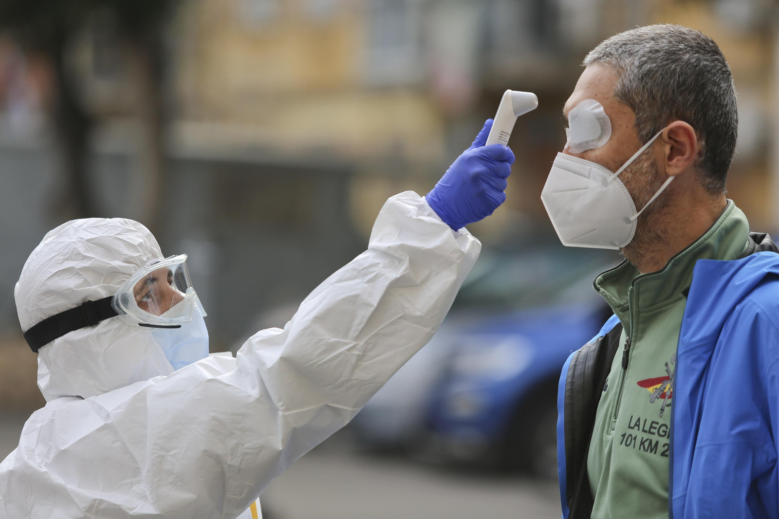 Una sanitaria toma la temperatura a un hombre en un cribado masivo.