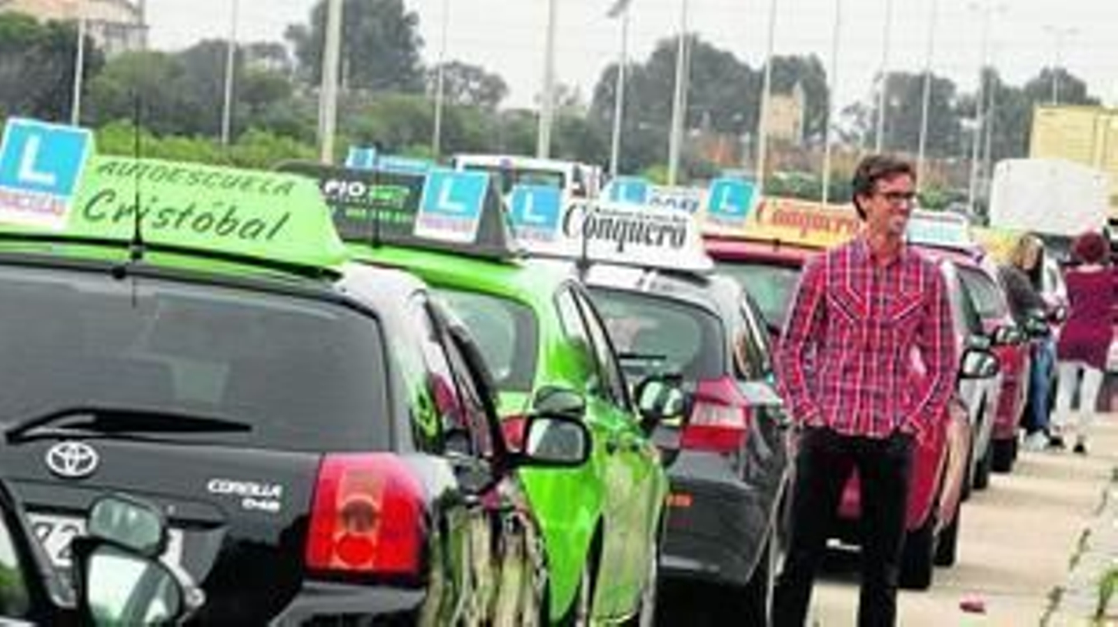 Fila de coches de varias autoescuelas en Marismas del Polovrín, justo antes de recorrer varias calles de la ciudad.