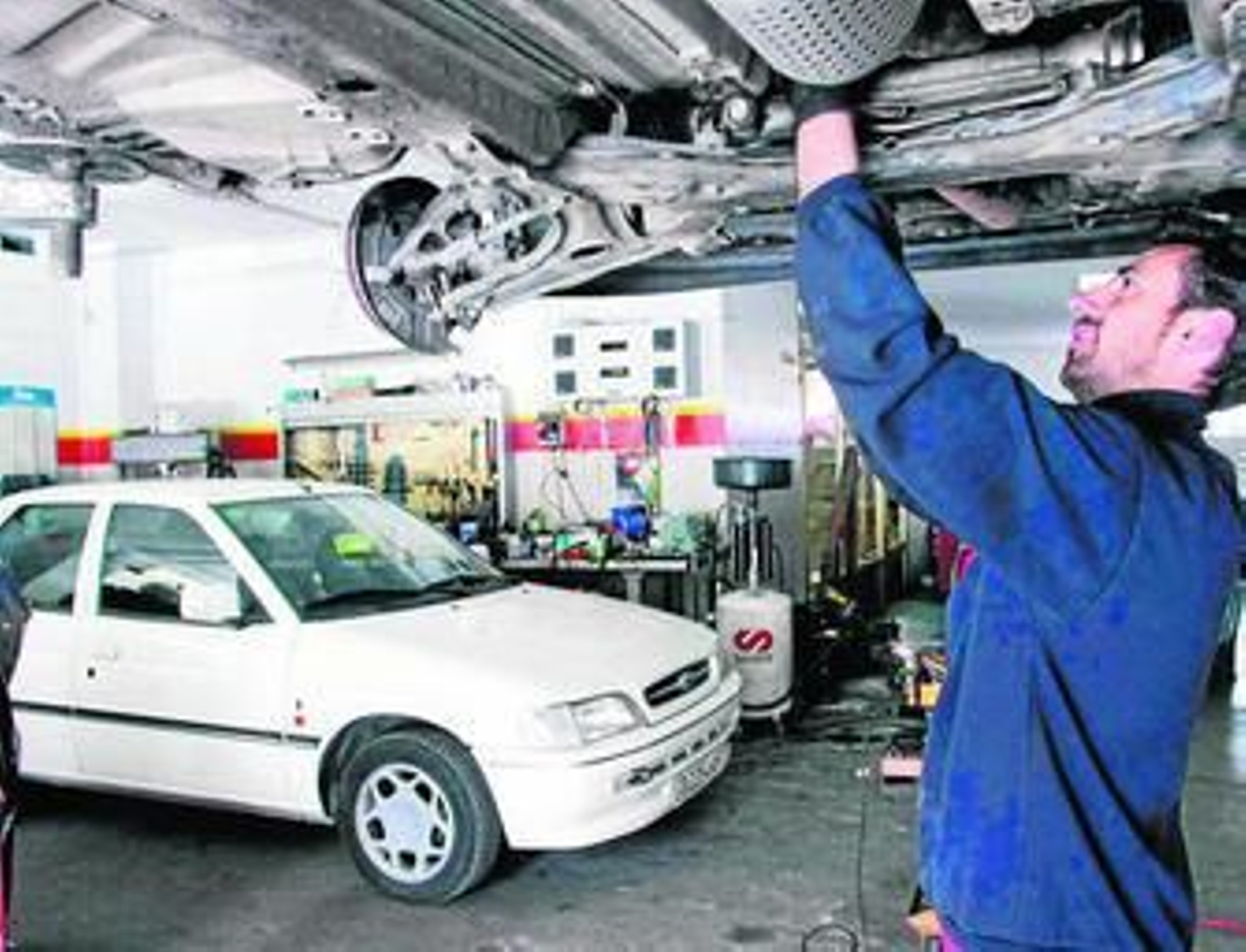 Un mecánico repara algunos vehículos en su taller.