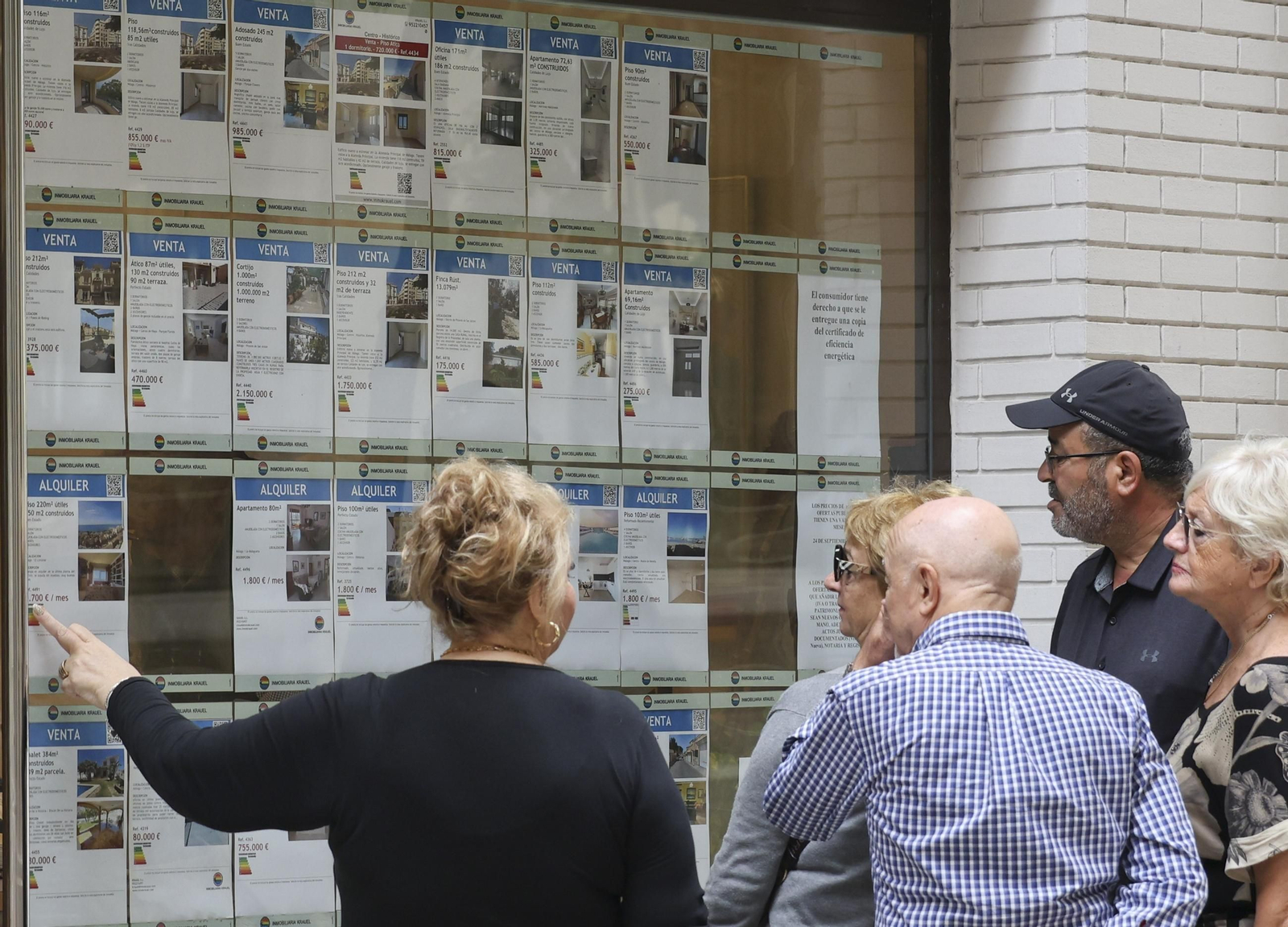 Un grupo mira el escaparate de una inmobiliaria en Málaga, con viviendas en alquiler y venta. Un grupo mira el escaparate de una inmobiliaria en Málaga, con viviendas en alquiler y venta.