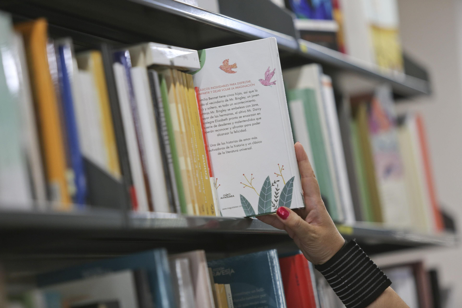 Una persona coge un libro de una estantería.