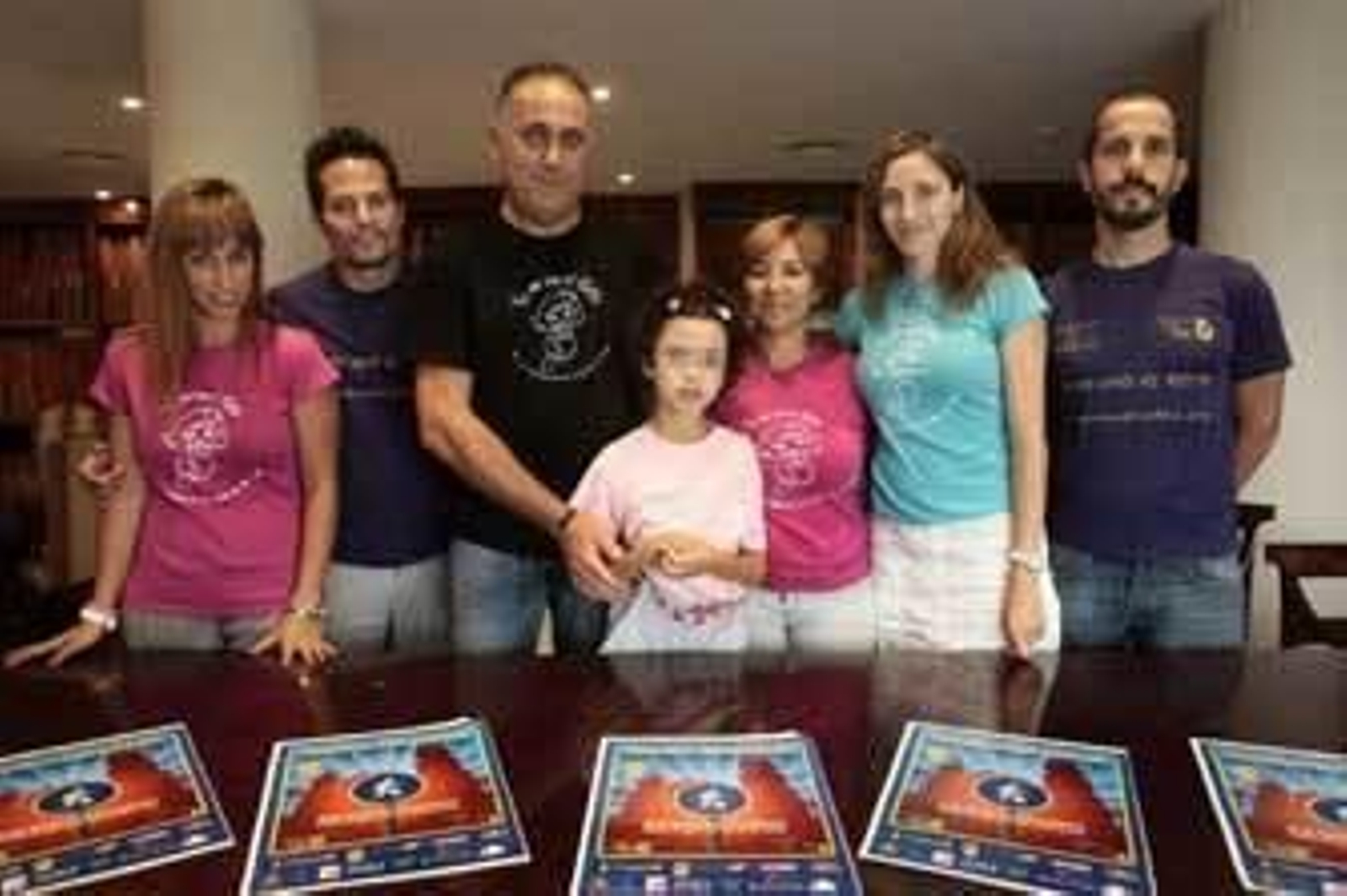 Las tres parejas aparecen en la foto con los carteles del acto solidario del sábado con Paula en el centro, afectada por el Síndrome de Rett. /Fito Carreto