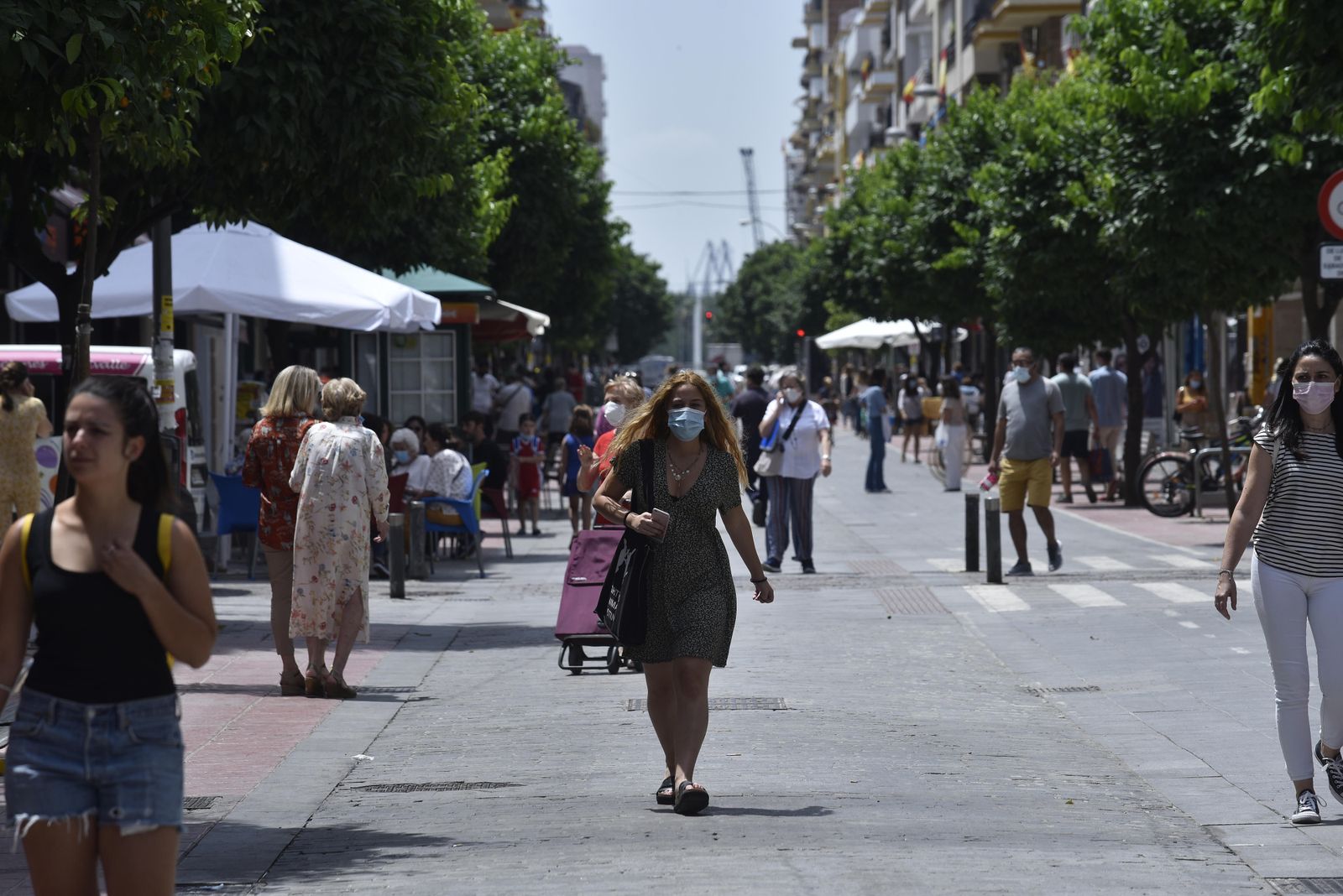 Varios viandantes guardan la distancia de seguridad mientras caminan por una calle peatonal de la ciudad.