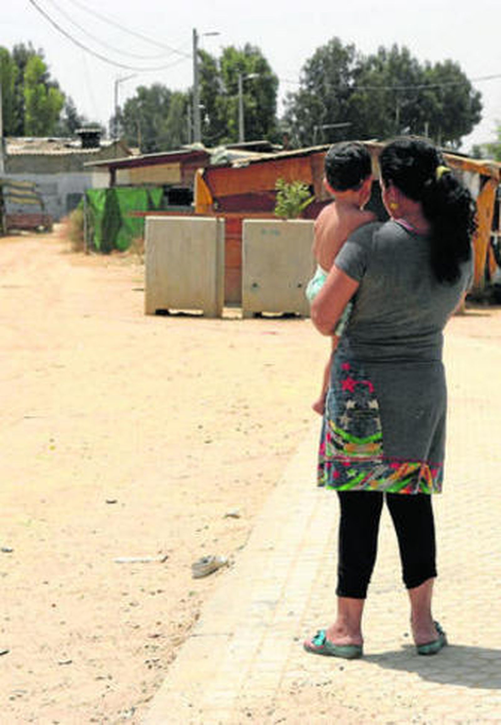 Una vecina del Vacie mira hacia el interior del poblado con su hijo en brazos.