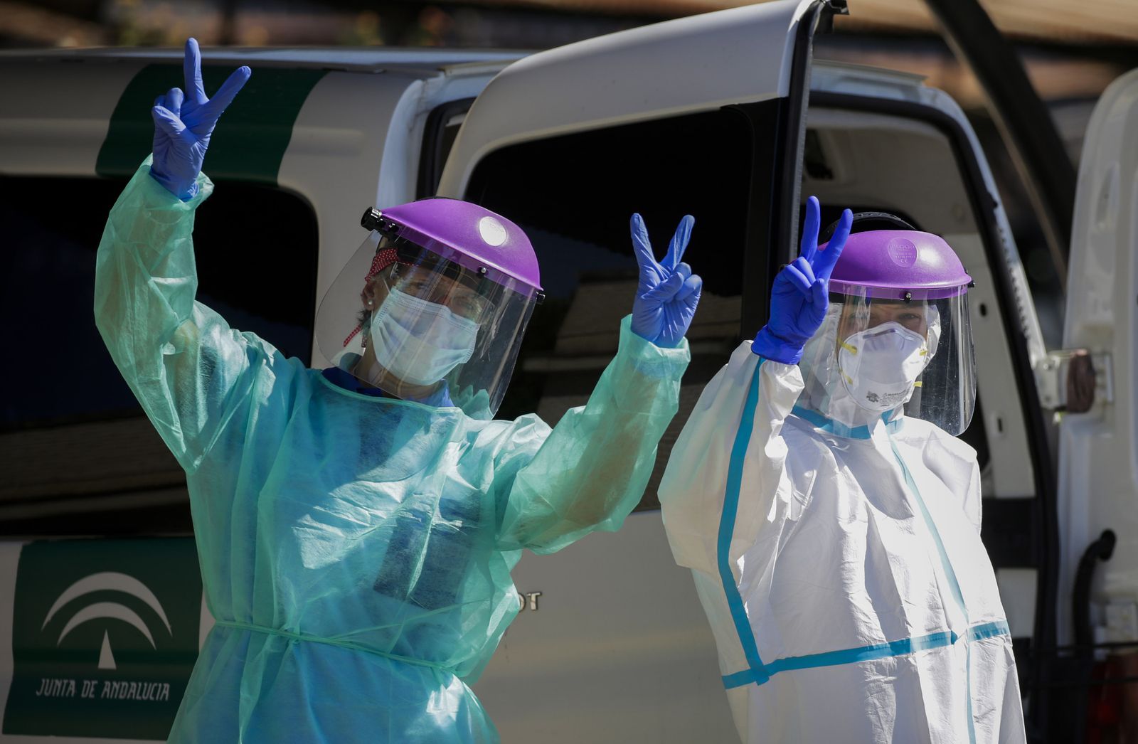 Dos sanitarias, vestidas con los EPIS, hacen el símbolo de victoria.