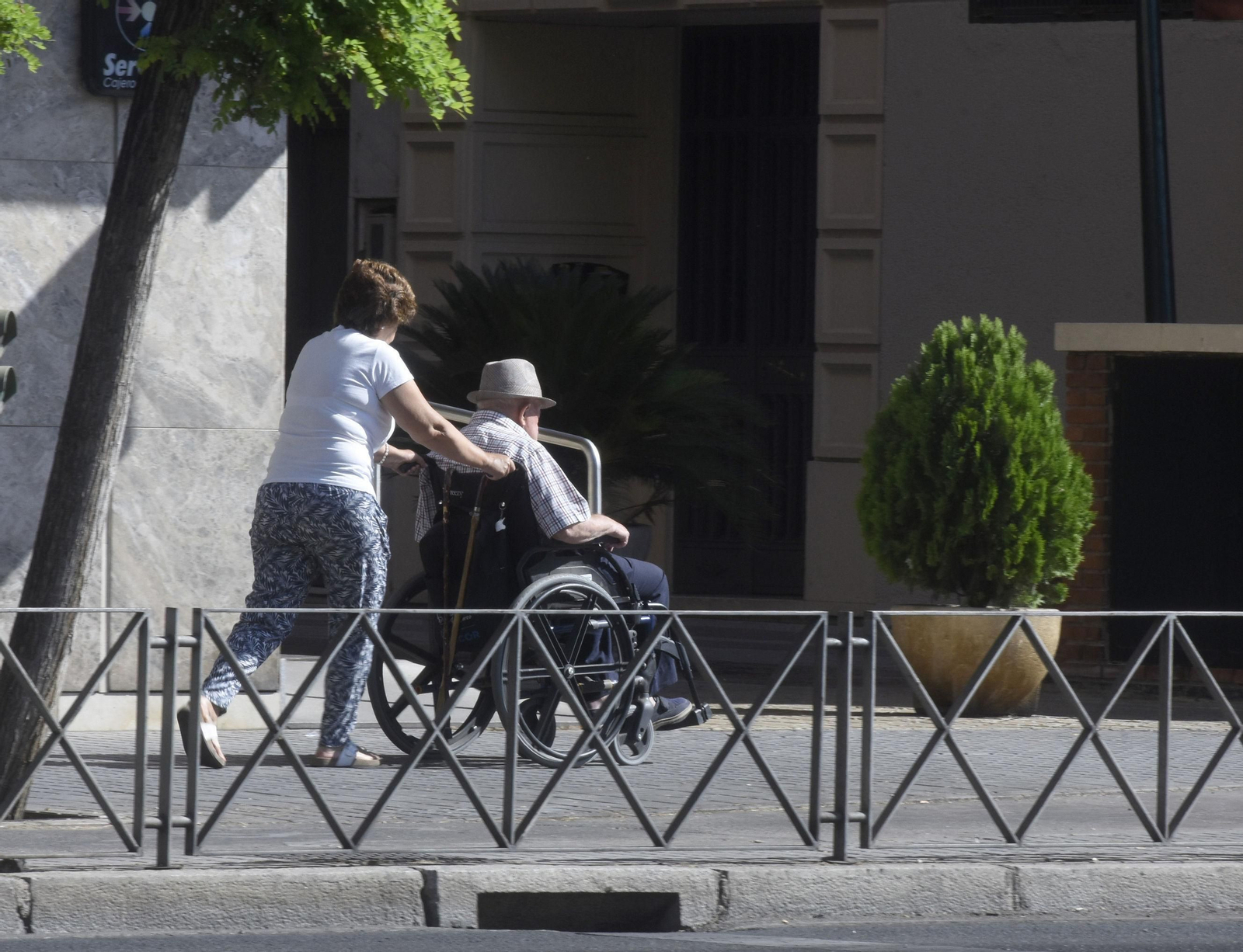 Una mujer pasea con un hombre en silla de ruedas.