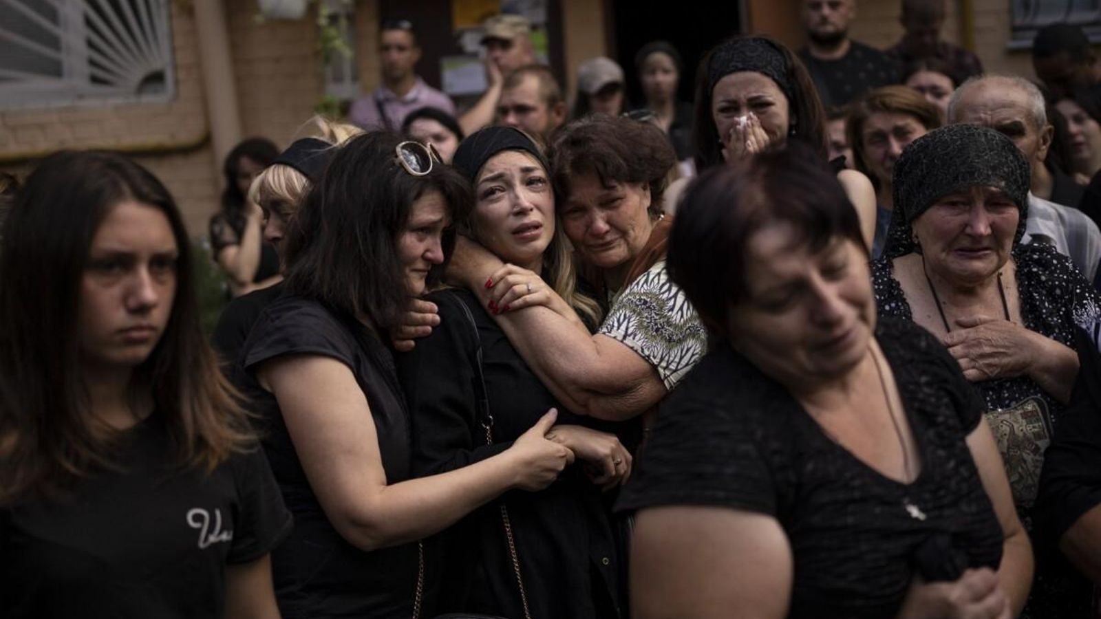 Anastasia Ohrimenko, de 26 años, es consolada por familiares y amigos mientras llora junto a un ataúd con el cuerpo de su esposo Yury Styglyuk, militar ucraniano que murió en combate el 24 de agosto en Maryinka, Donetsk, durante su funeral en Bucha, Ucrania. miércoles, 31 de agosto de 2022. (Foto de Emilio Morenatti.)