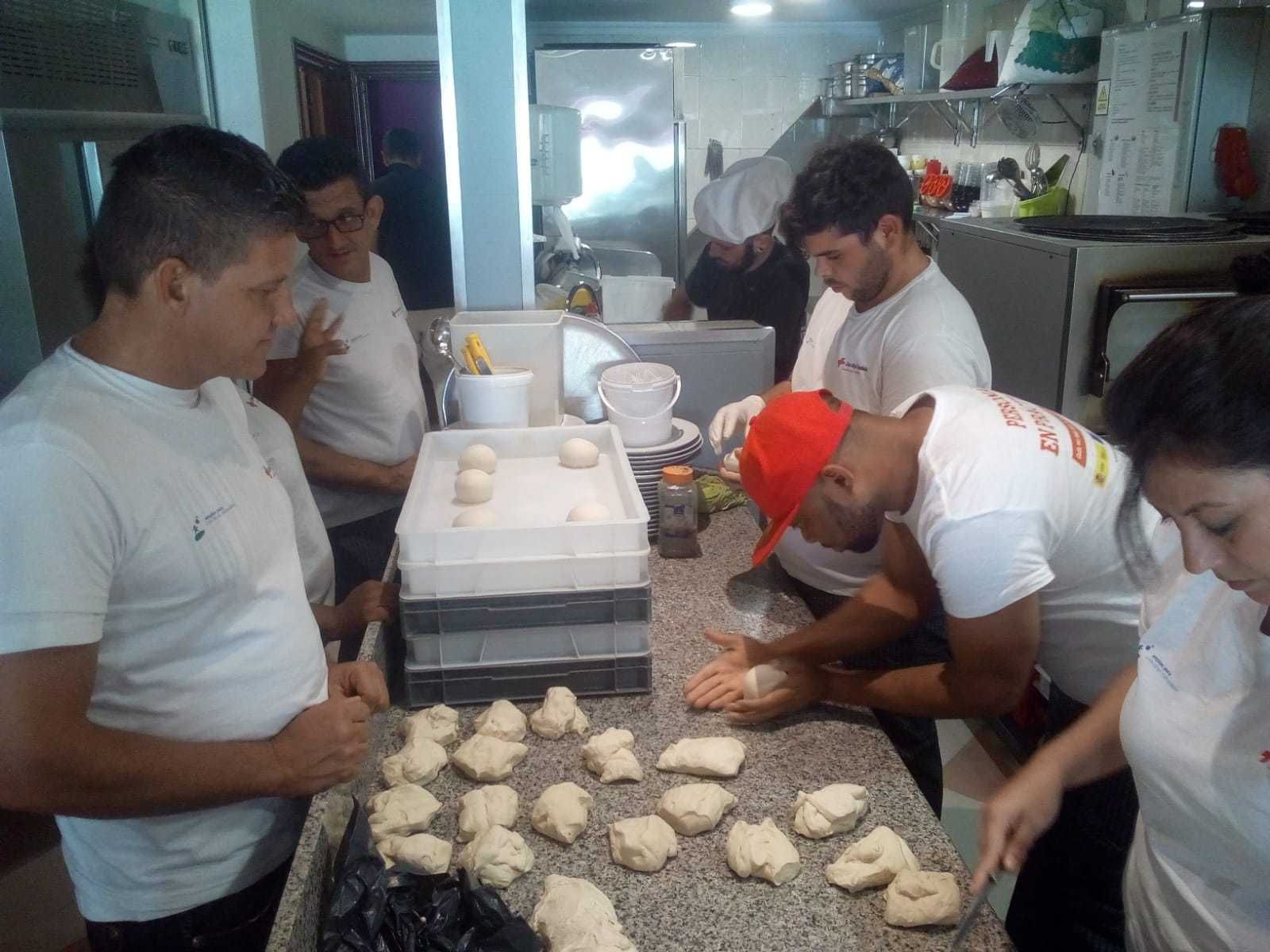 Participantes en el curso de pizzero de Cruz Roja preparan la masa en una clase práctica en L' Albero.