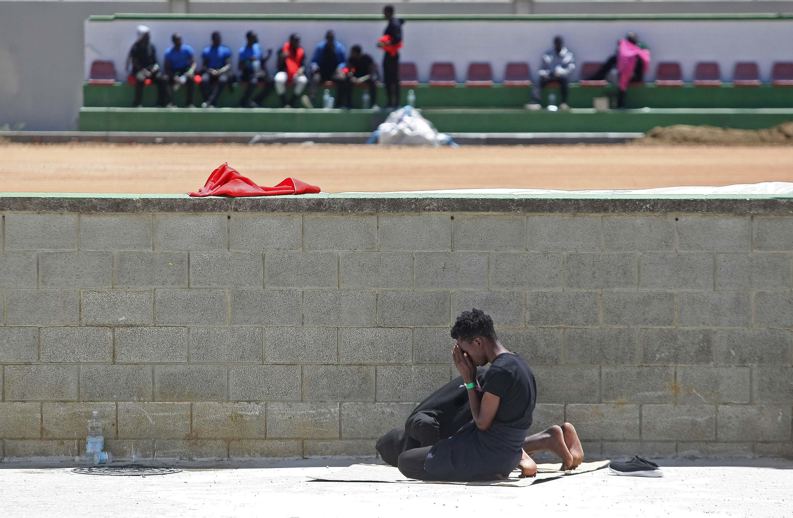 Dos personas rezan junto a un muro en el polideportivo de Los Cortijillos.