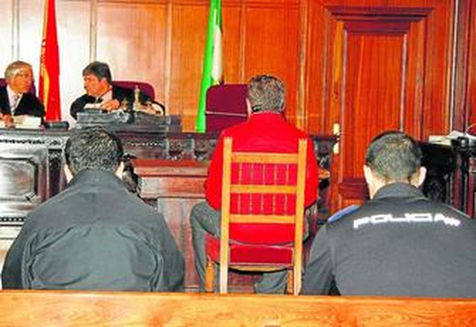 El acusado, de espaldas y custodiado por la Policía, en la primera sesión del juicio.