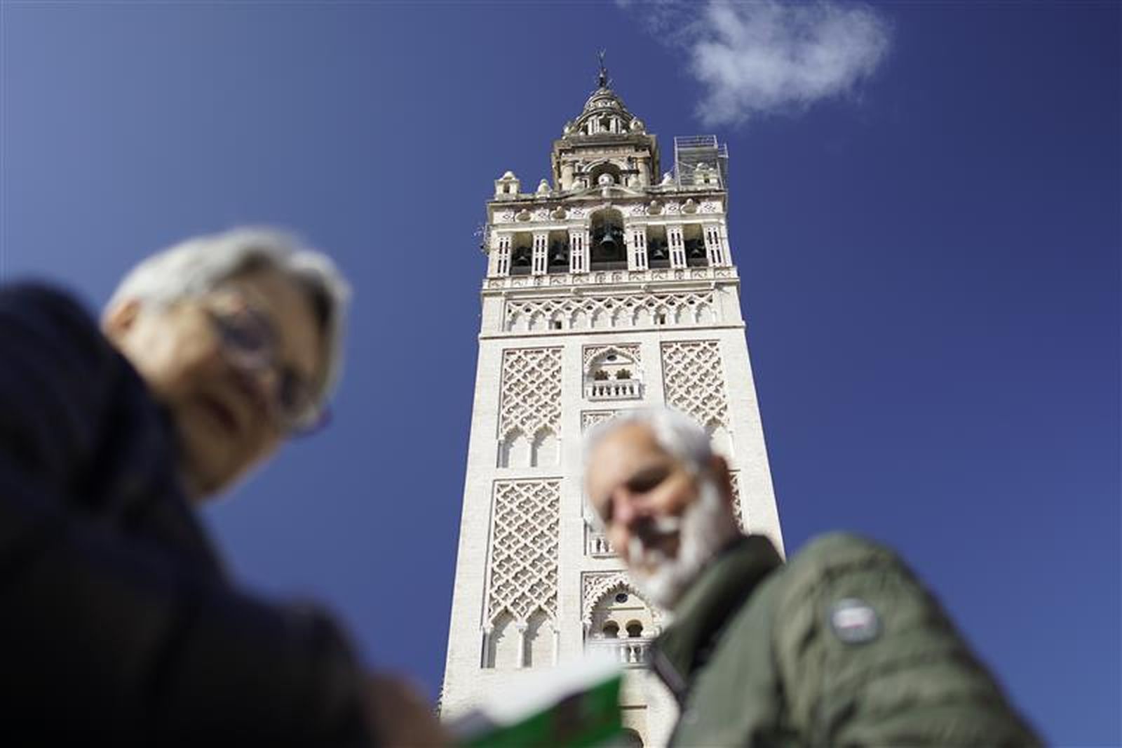 Dos turistas bajo la Giralda el día previsto para la retirada de las tres azucenas restantes.