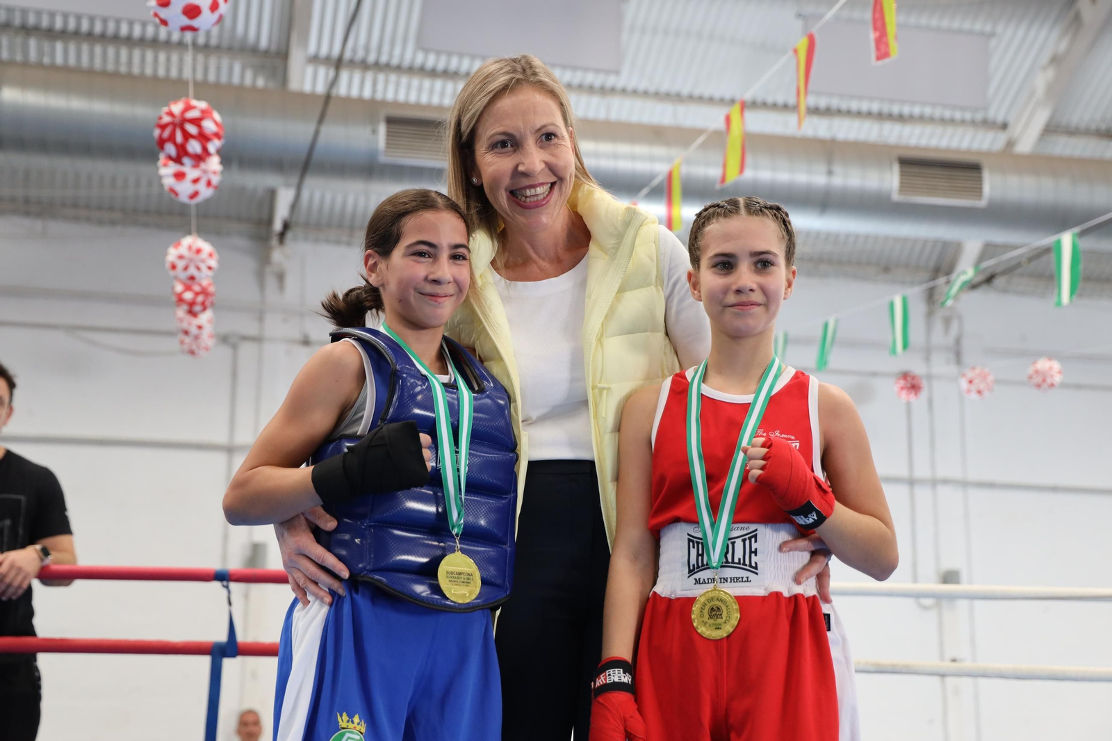 Dos de las boxeadoras participantes en el III Open de Andalucía en edad escolar posan junto a la edil con sus medallas.