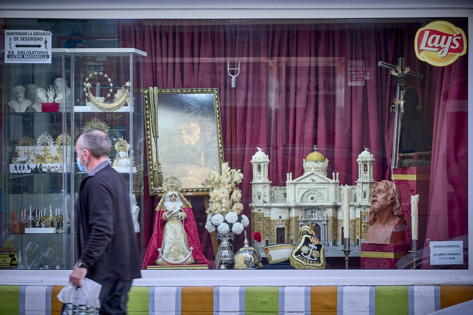 Un hombre pasa delante del escaparate cofrade de Óscar Jiménez.
