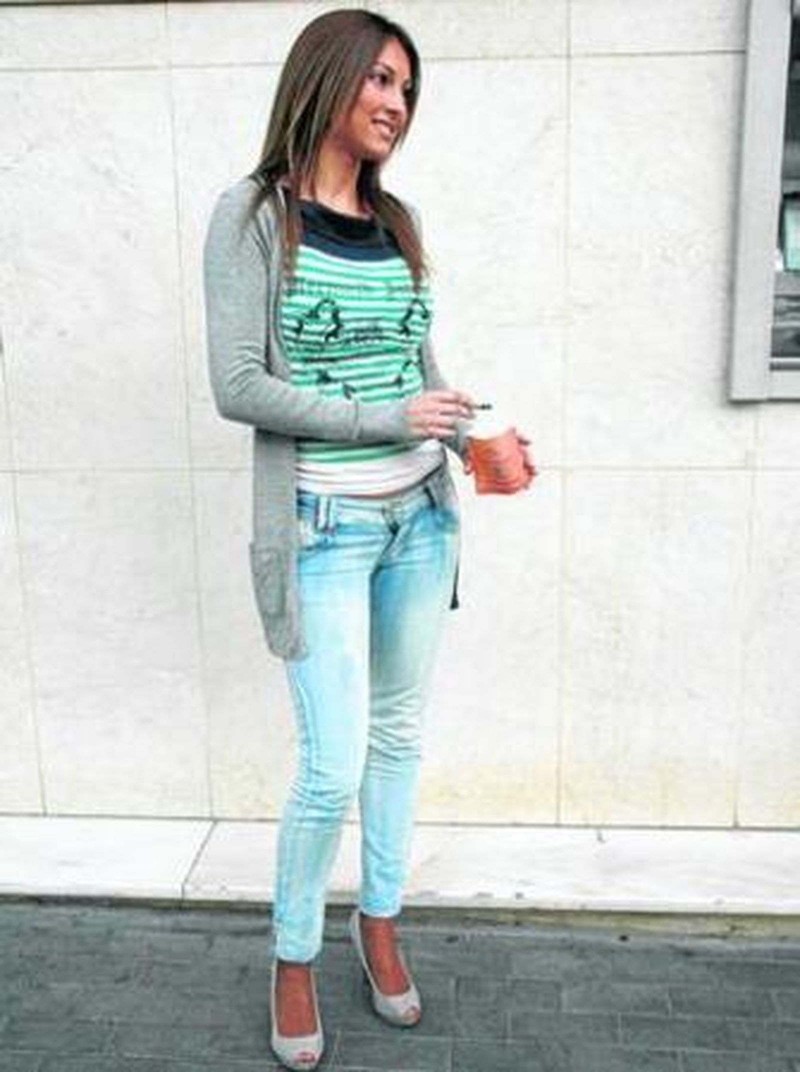 Una fumadora en la puerta de un bar con el cenicero ecológico del bolsillo en la mano.