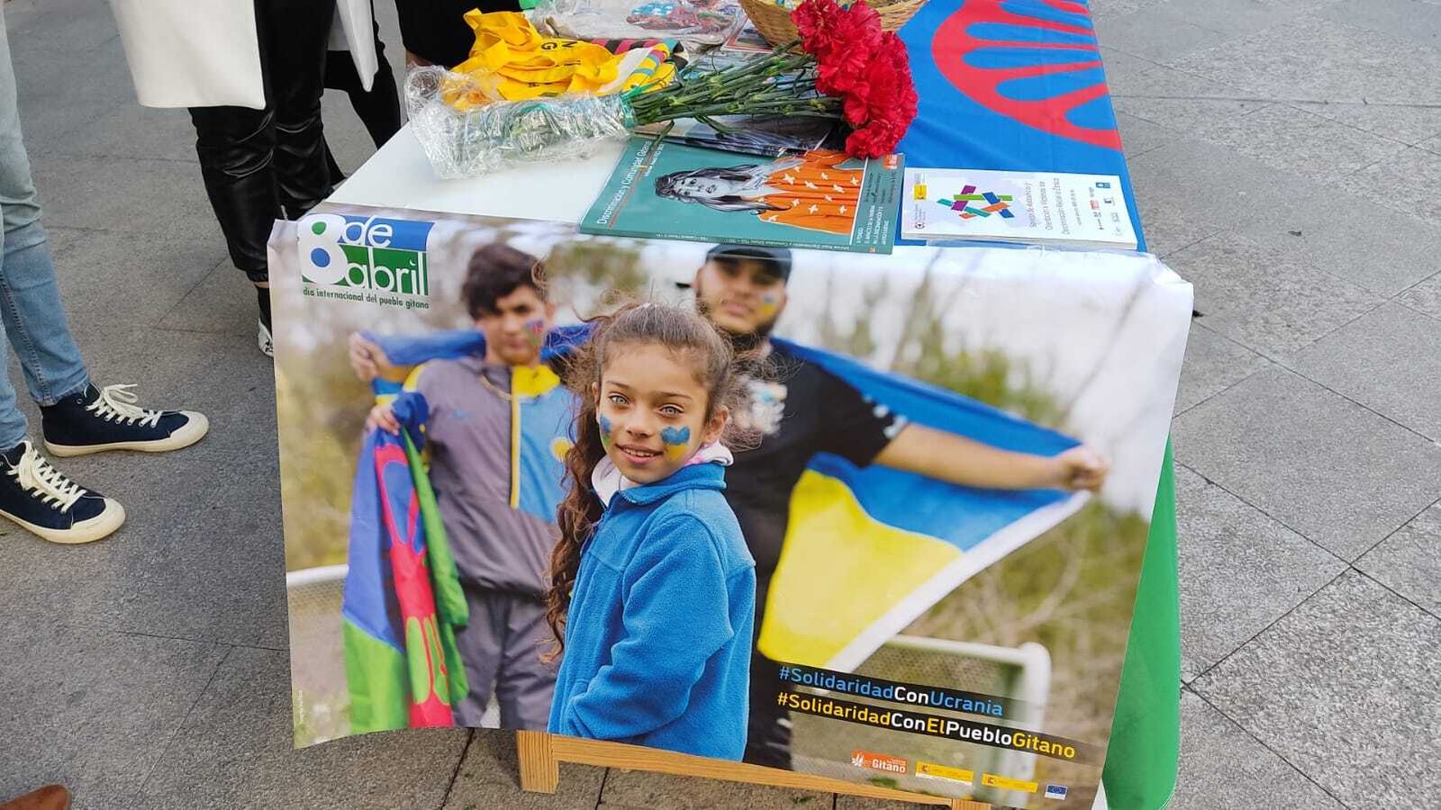 Cartel y claveles del Día Internacional del Pueblo Gitano, en una de las mesas de la Fundación Secretariado Gitano de Jerez.
