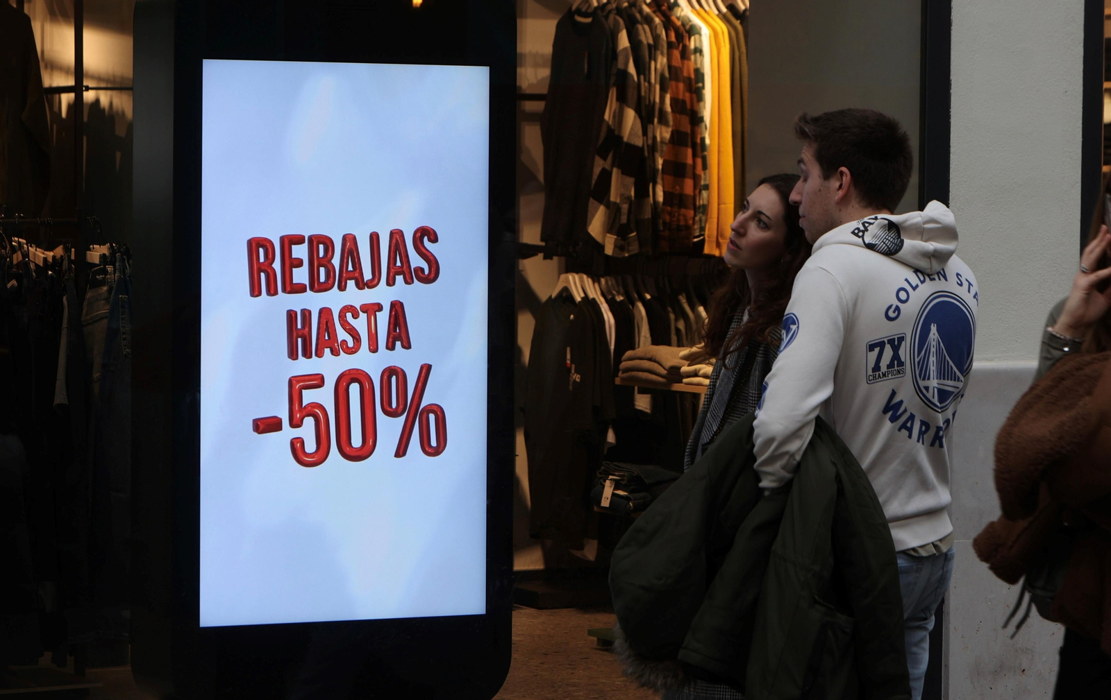 Dos jóvenes ante un cartel con descuentos