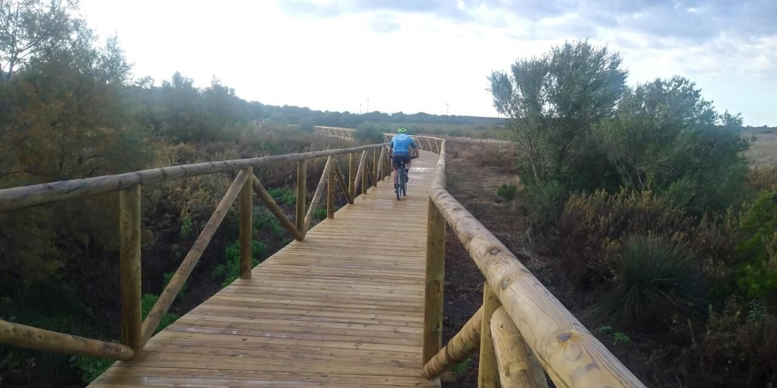 Un ciclista cruza la nueva pasarela de madera en la zona inundable de la laguna Jeli.