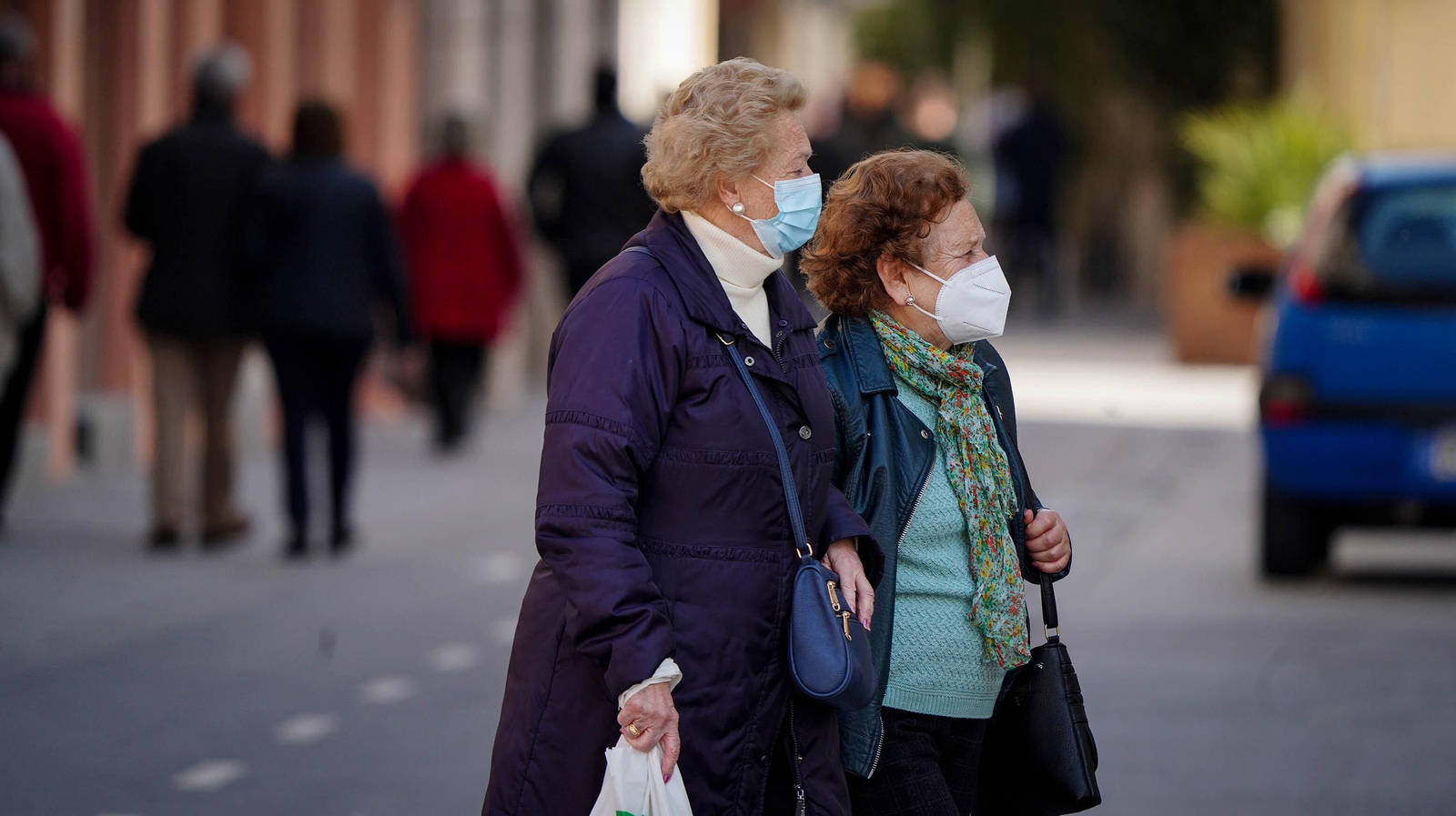 Dos mujeres cruzan una calle del centro con la mascarilla puesta.