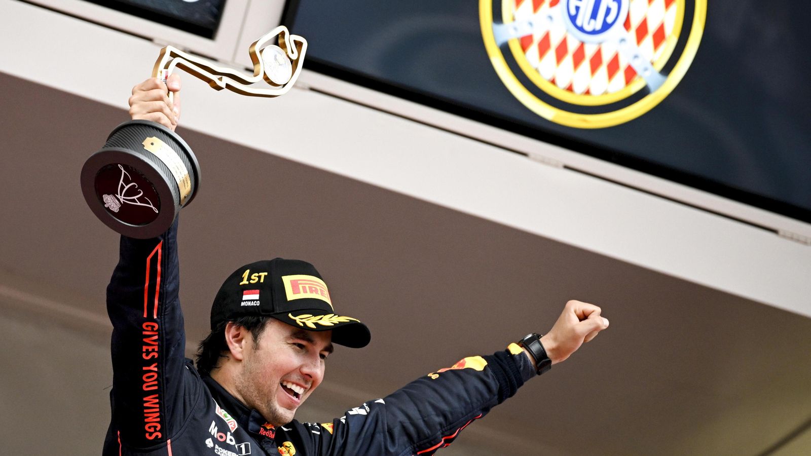 Checo levanta los brazos y su trofeo en lo más alto del podio.