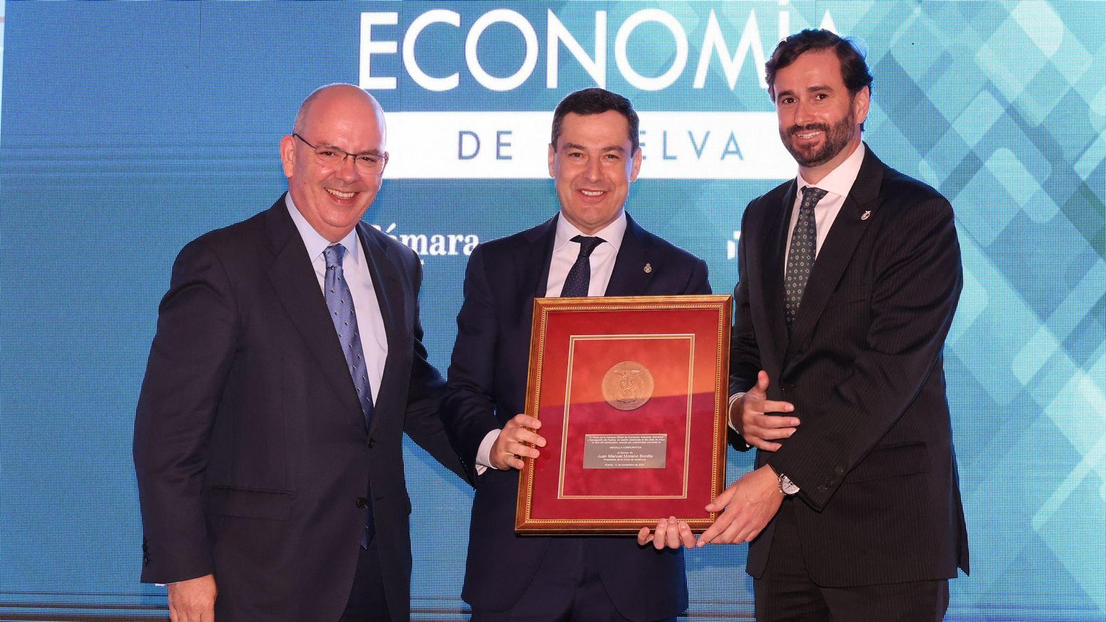 El persidente del Consejo andaluz de Cámaras de Comercio, Javier Sánchez Rojas, el presidente de la Junta de Andalucía Juanma Moreno y el presidente de la cámara de comercio de Huelva, Daniel Toscano.