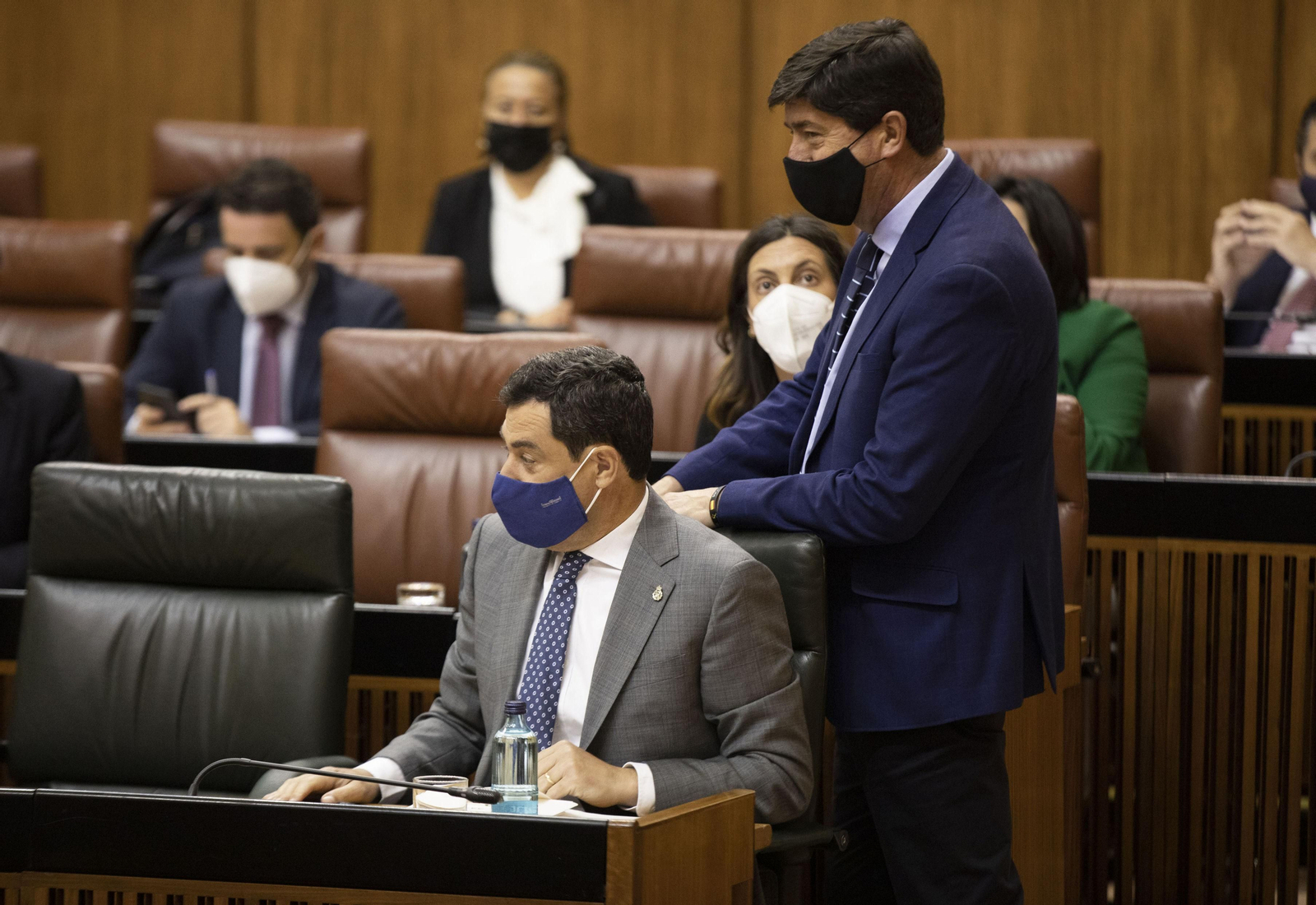 Juan Marín pasa a su sitio en el Parlamento, junto a Juanma Moreno.