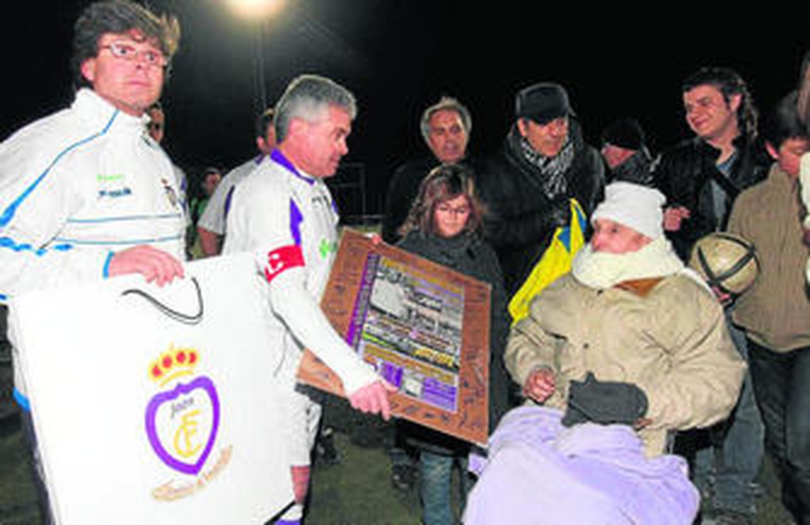 García Ojeda, al que una bufanda cubre parte de su rostro, recibe recuerdos de los veteranos del Jaén.