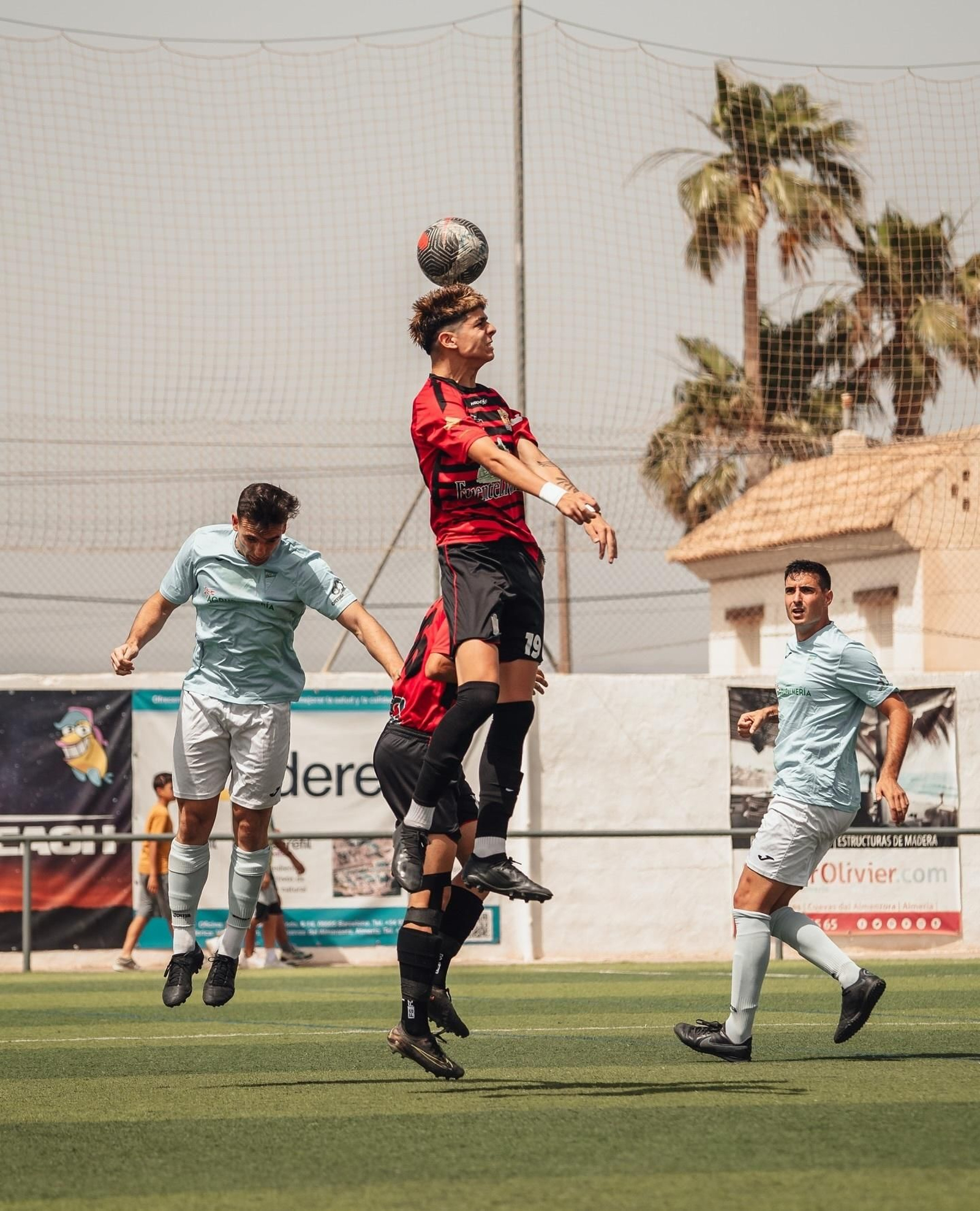 Un jugador del Cuevas golpea de cabeza un balón en una disputa con un futbolista celeste.