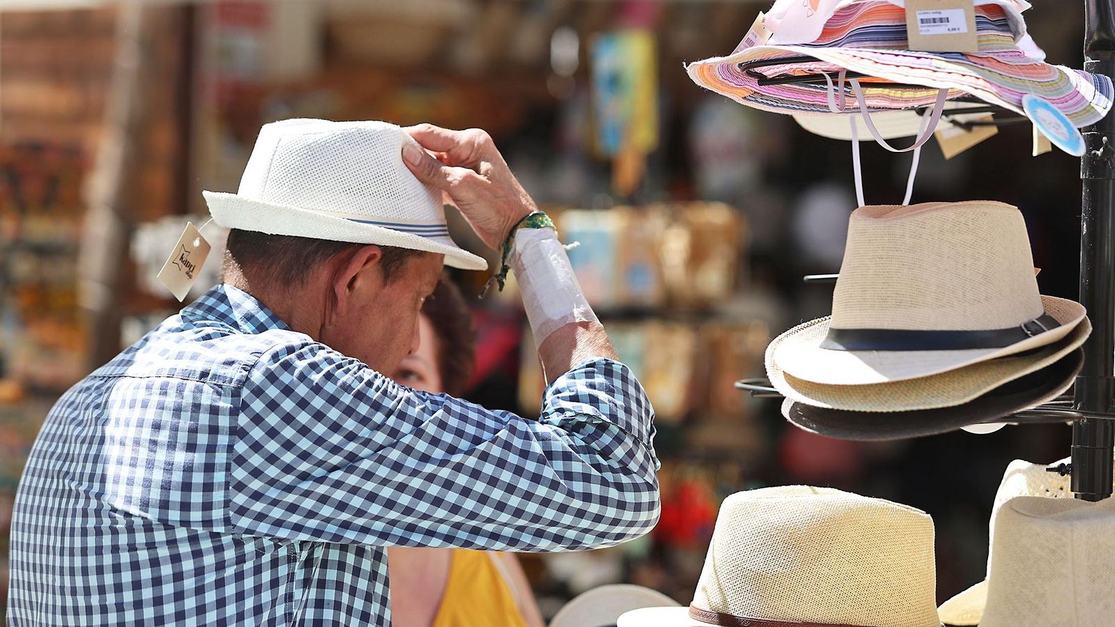 Un hombre se prueba sombreros durante un día de sol.
