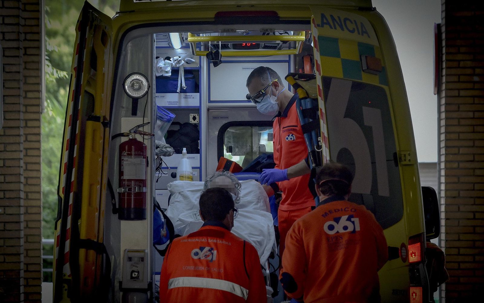 Sanitarios del 061 bajan de una ambulancia a un paciente en las Urgencias.