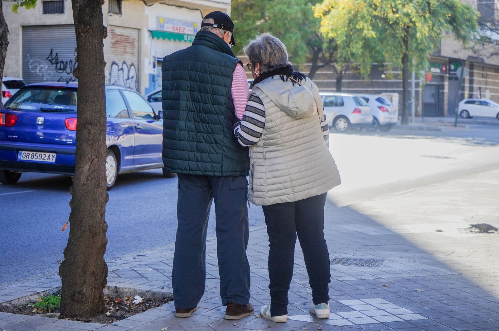 Un matrimonio observa el móvil parados en una calle de Granada.