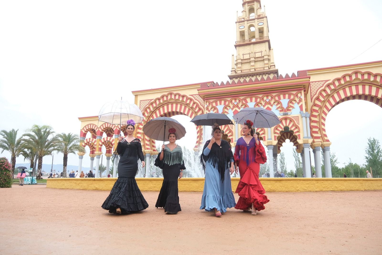 Varias mujeres llegan a la Feria de Córdoba bajo la lluvia.