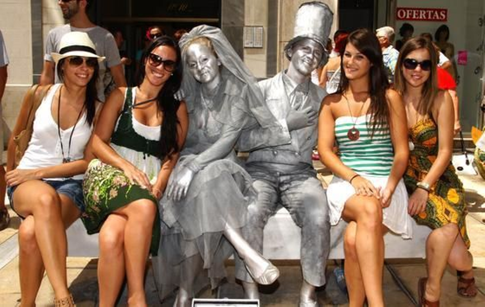 Unas jóvenes extranjeras posan junto a dos mimos en calle Larios. 

Foto: Punto Press