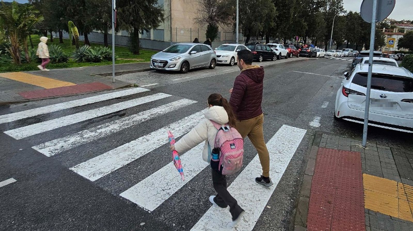 Una pequeña, acompañada, se dirige a su colegio