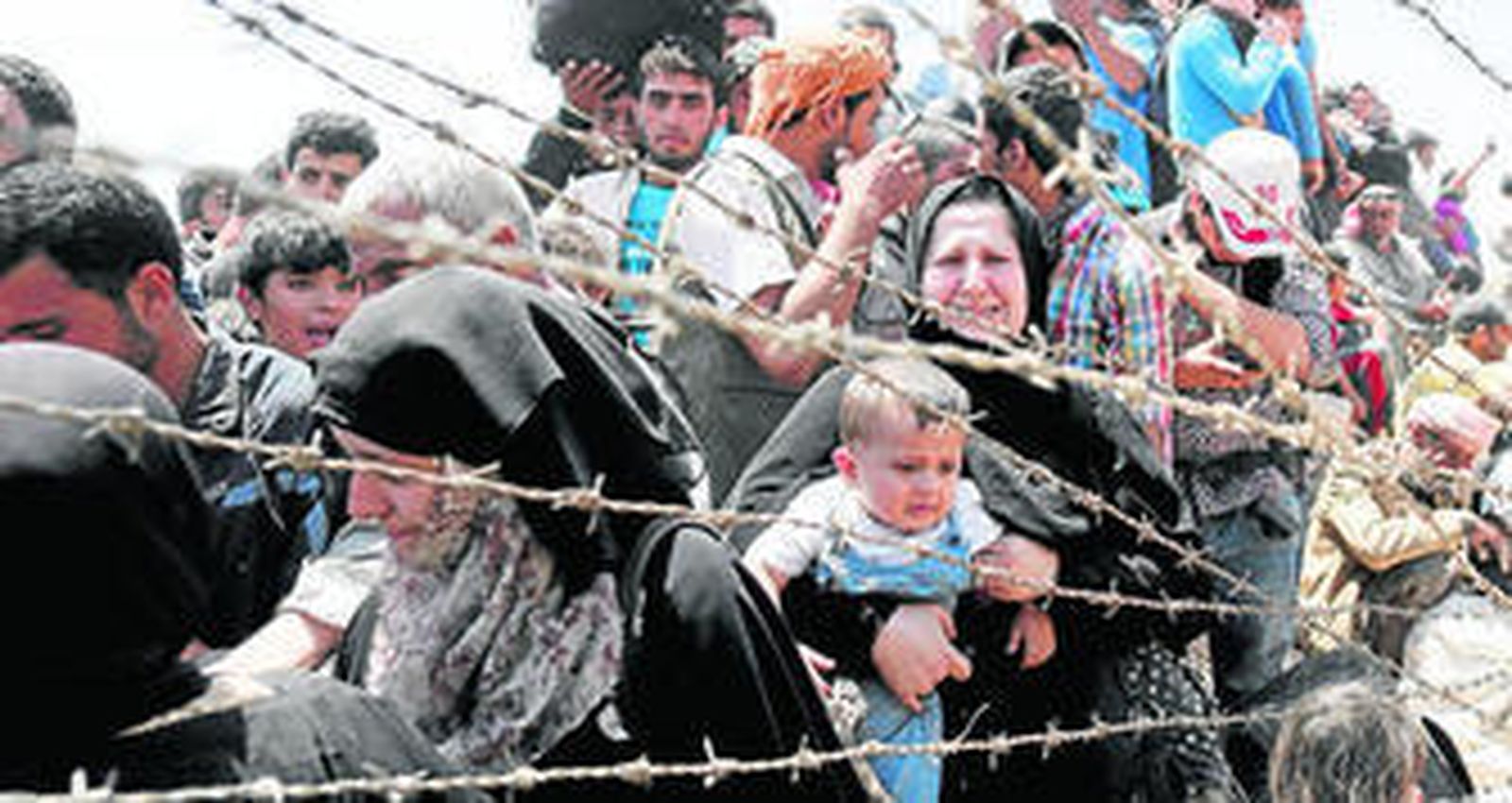 Refugiados sirios esperando para cruzar desde su país la frontera que les separa de Turquía.