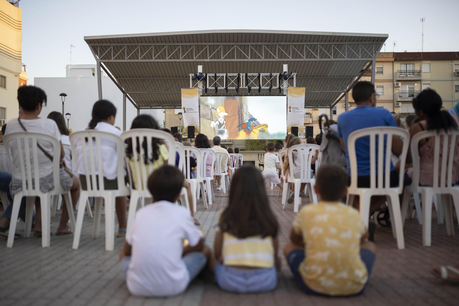 Niños disfrutan de la película proyectada en un cine de verano.