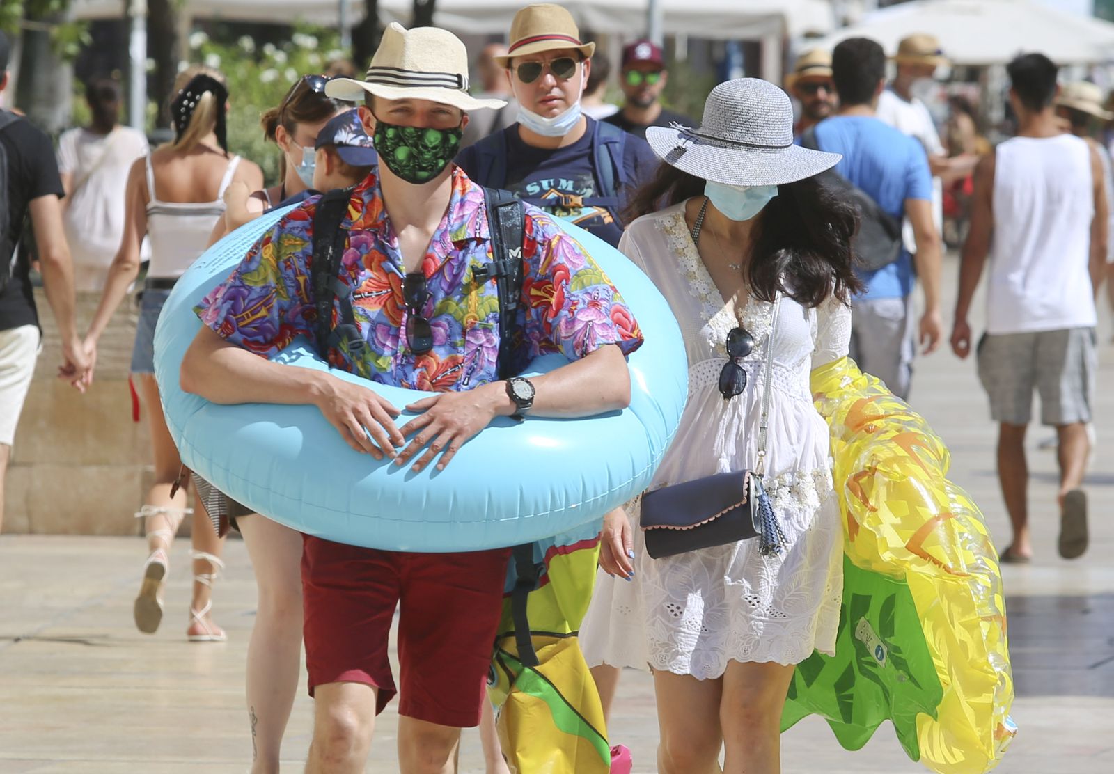 Personas con flotadores, caminando por el centro de Málaga.