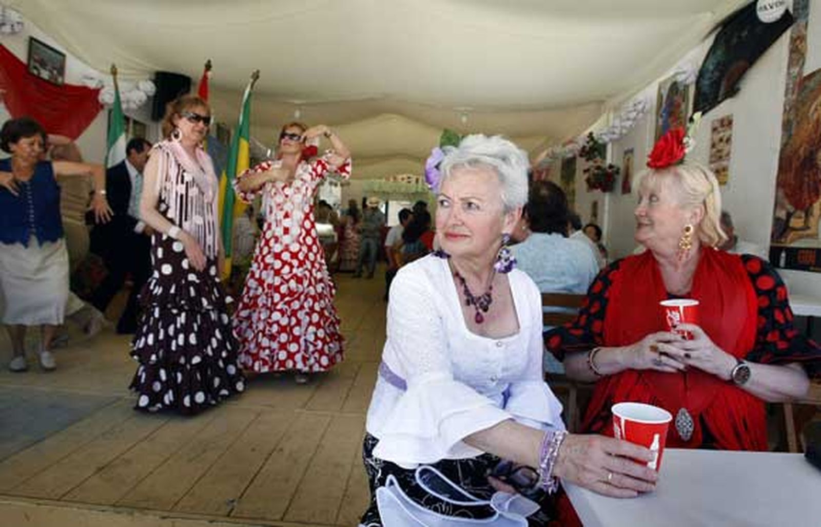 Dos mujeres vestidas de flamencas toman un refresco en la caseta de la Tercera Edad

Foto: Fito Carreto