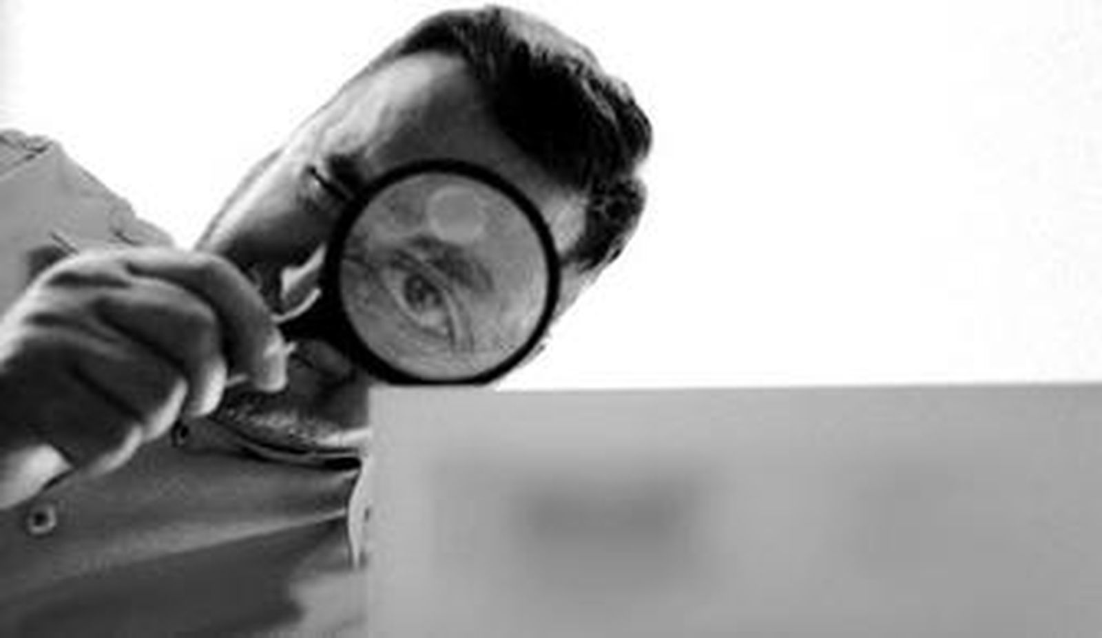 Un detective privado observa con una lupa una factura.