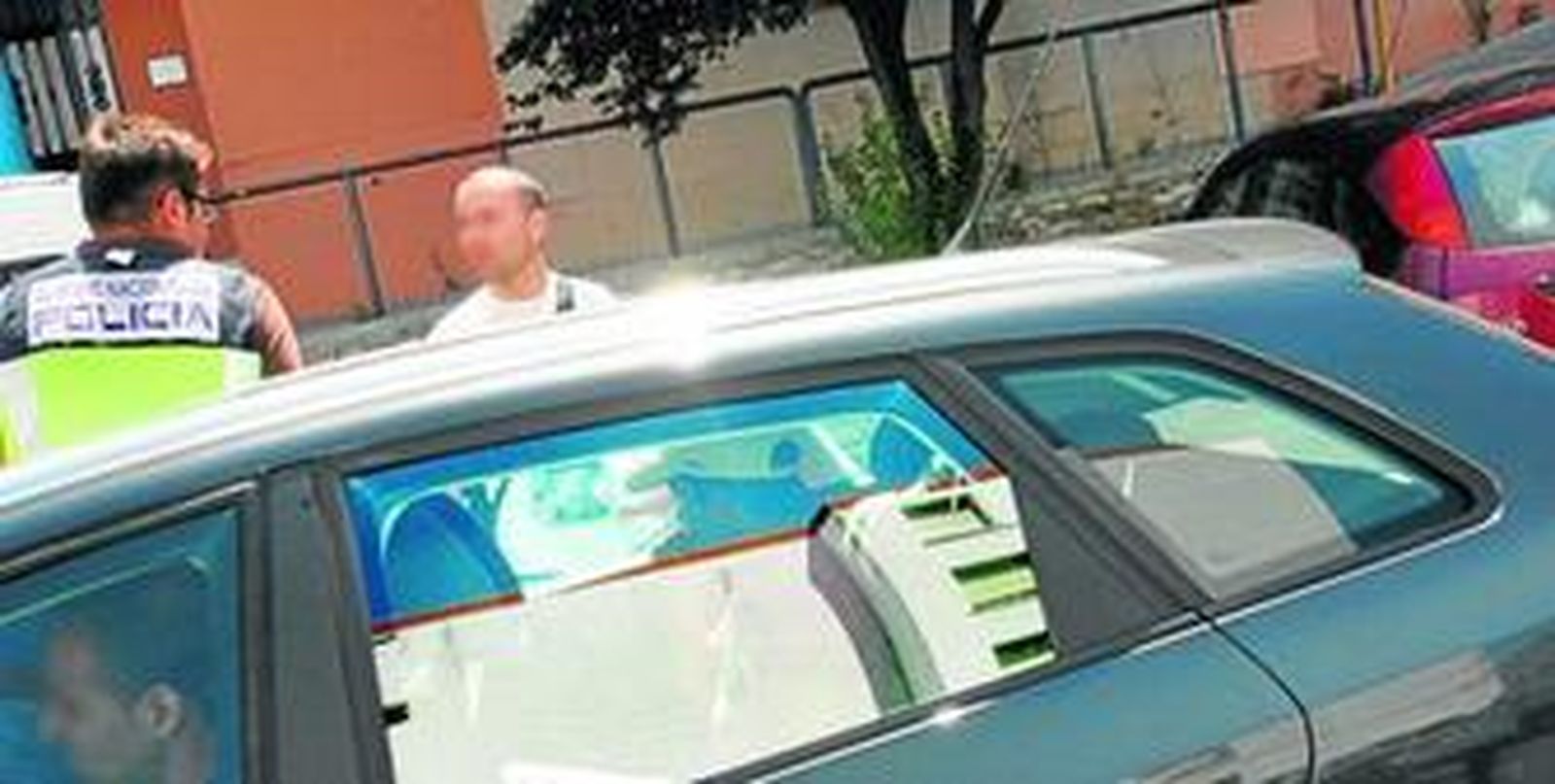 El padre del menor, en el coche, con gorra blanca, acompaña a la Policía tras el registro efectuado ayer en su domicilio.
