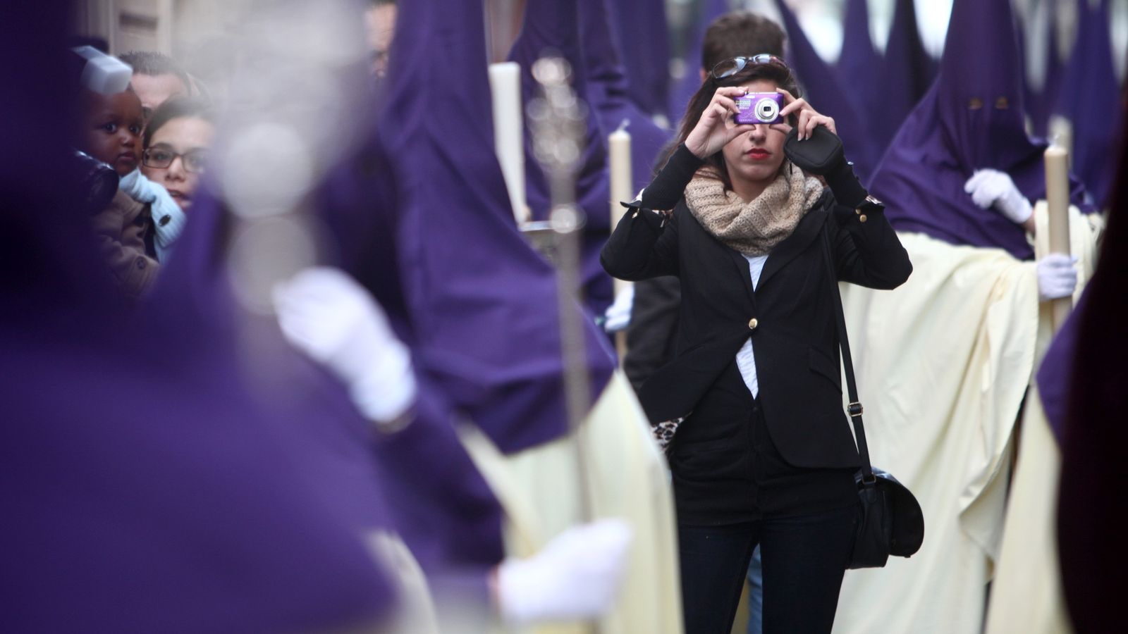 Una joven toma fotografías en medio de un cortejo.
