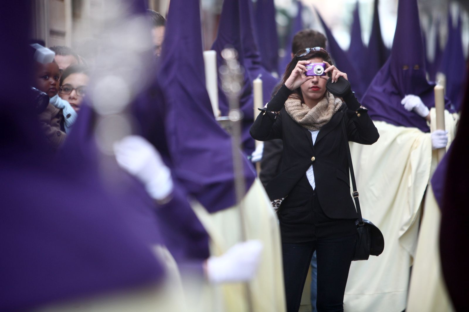 Una joven toma fotografías en medio de un cortejo.