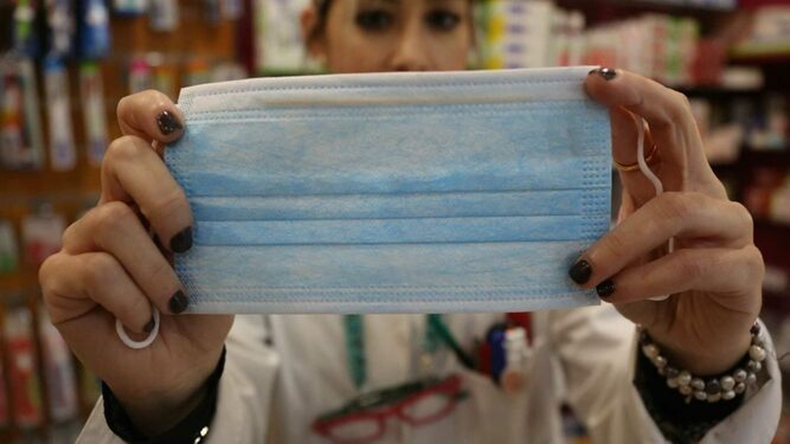 Una farmacéutica de Málaga muestra una mascarilla quirúrgica.